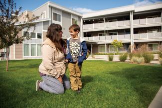 Woman and child on lawn in front of apartment building