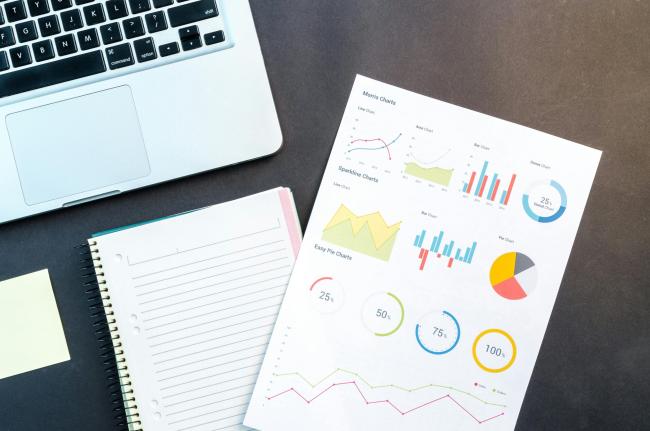 Desk with charts, a notebook, and a laptop